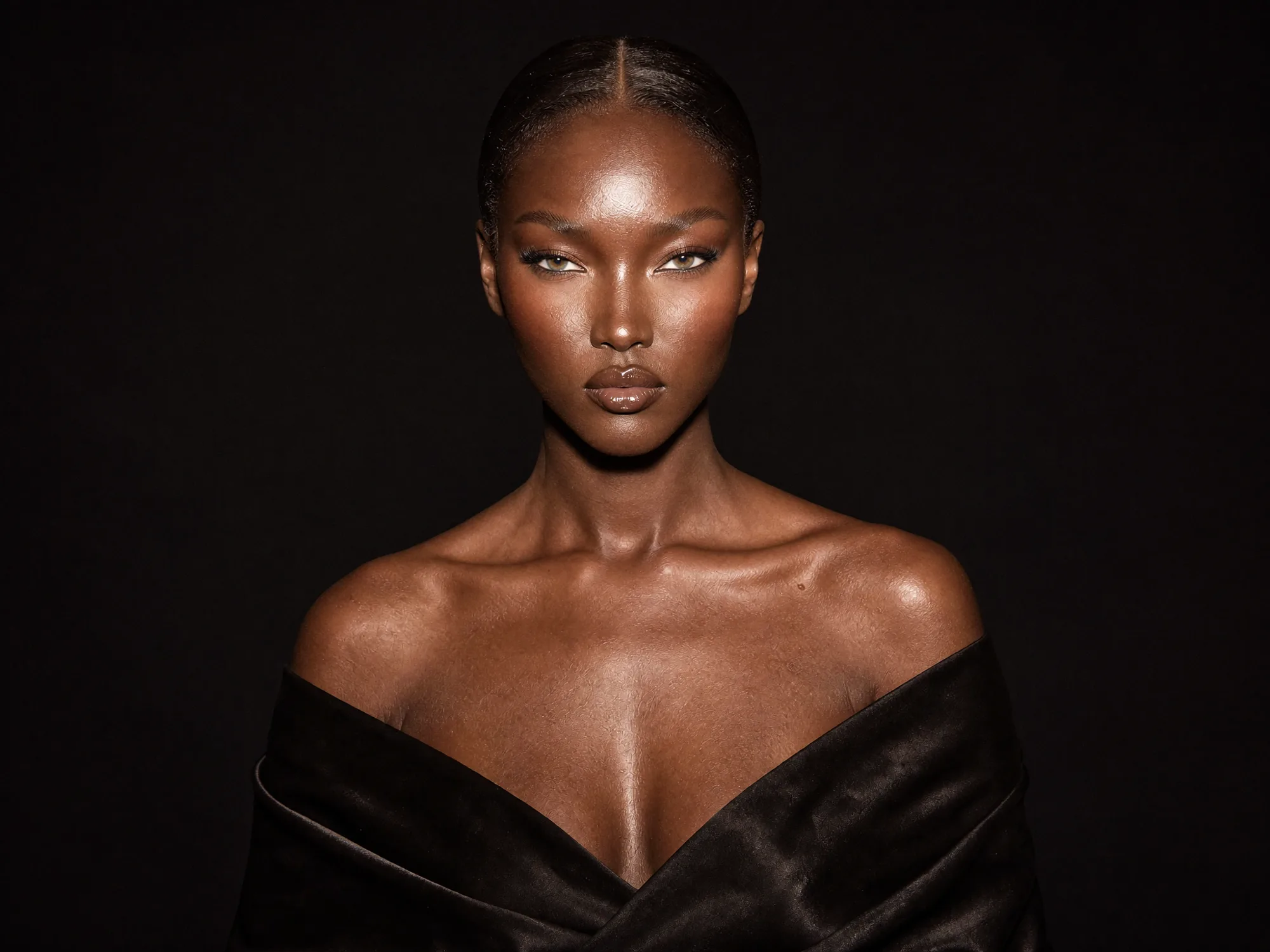 A portrait in a dark off-shoulder gown against a black ground