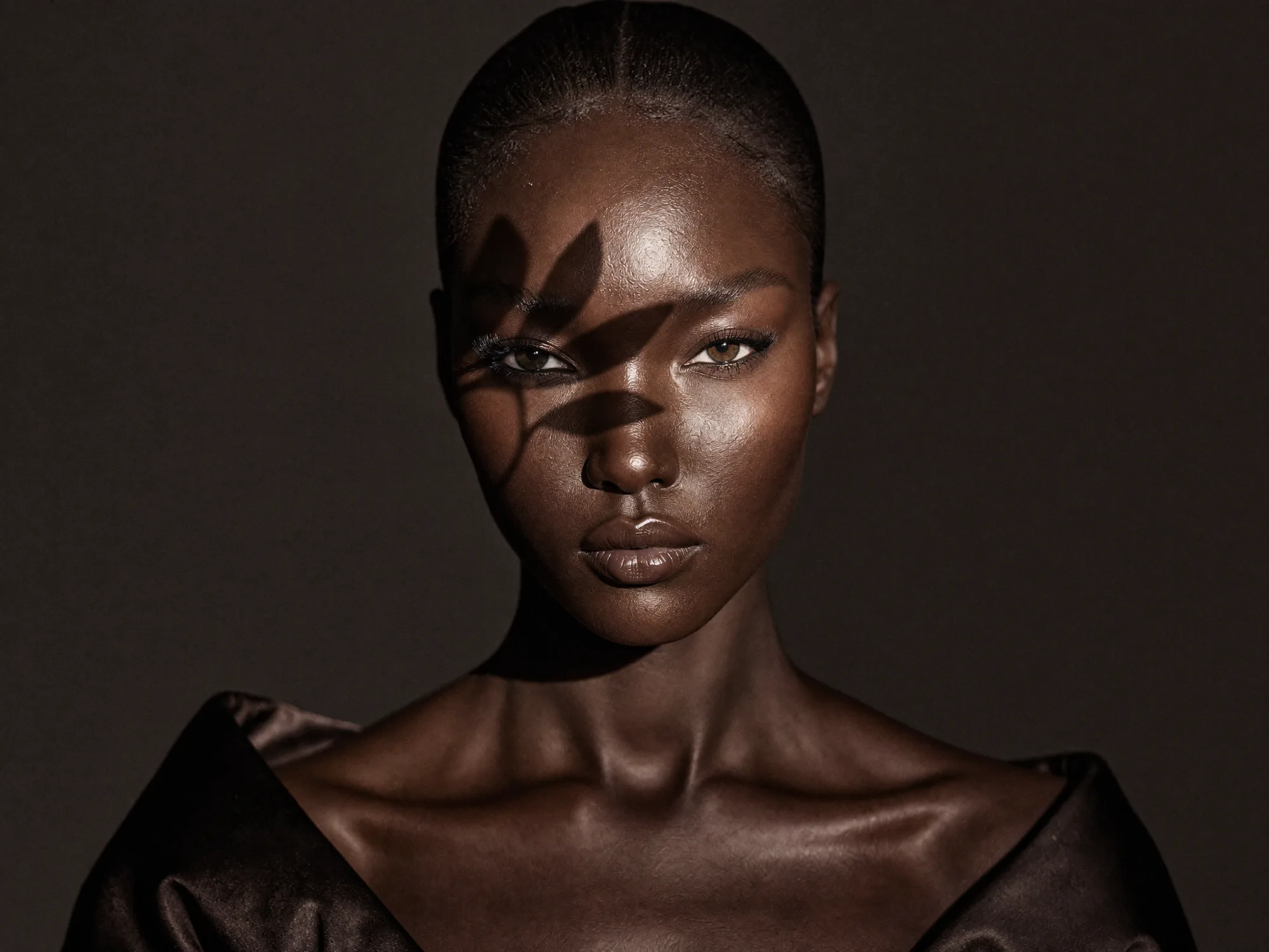 A model with sculptural dark fabric draped across one shoulder