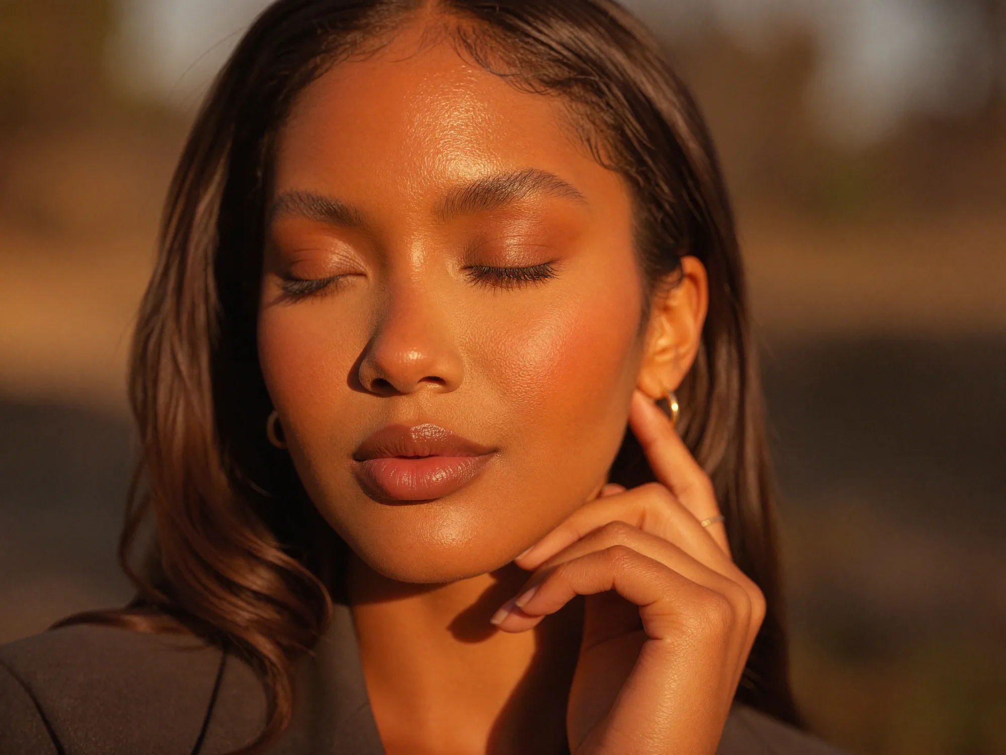 A close beauty portrait with a hand resting against the cheek in warm light